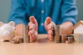 Divorce law and heritage separation concept. Hand separate saving money, financial, home loan, debt with piggy bank and wood house.