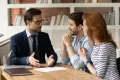 Professional male lawyer financial advisor consulting happy family couple clients in modern office.