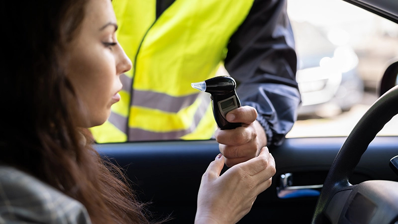 Policeman Doing Driver Alcohol Test Using Breathalyzer.