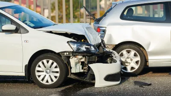 A white car with heavy front-end damage after a rear-end collision with a silver car.