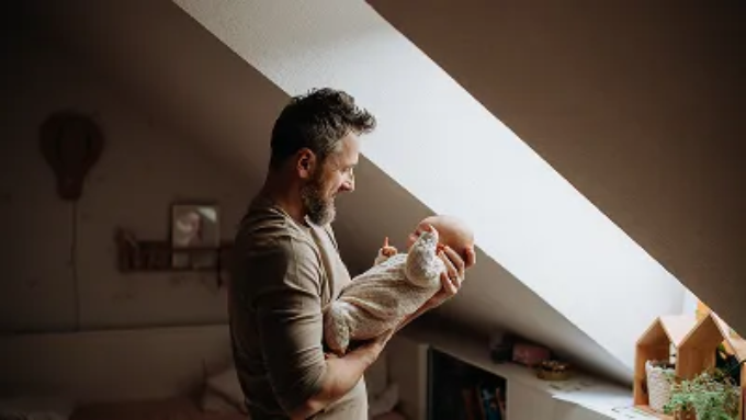 A man carrying his month old baby happily.