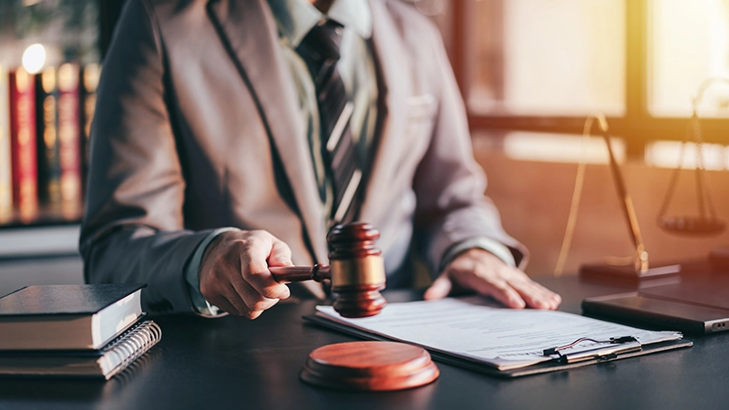 An attorney in suit holding a gavel in a law office.