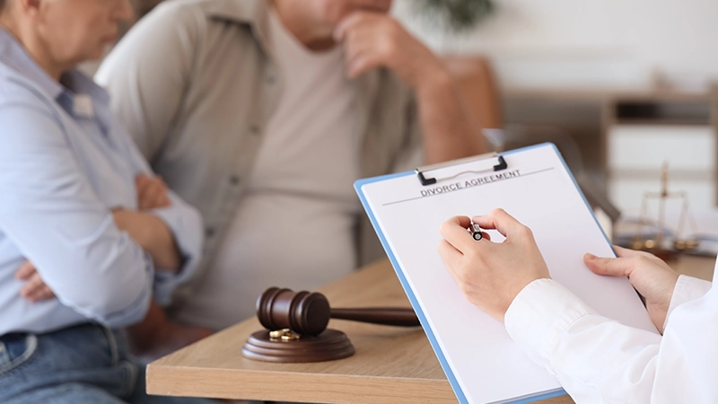 Female lawyer with divorce agreement and mature couple in office.